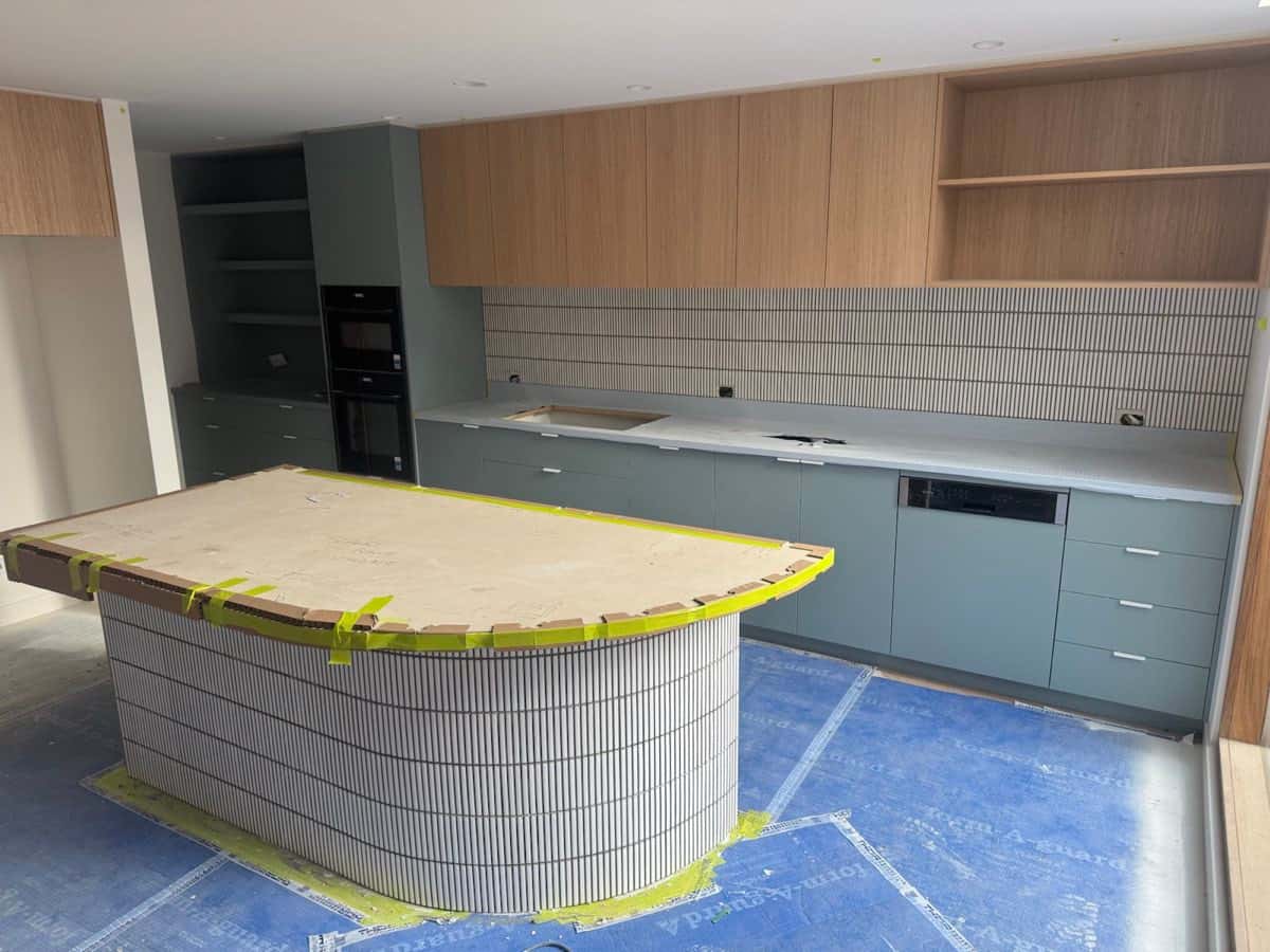 Kitchen with a curved island clad in narrow vertical feature tiles.