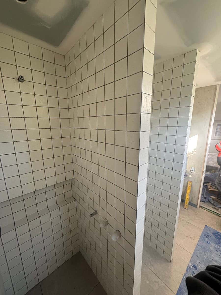 Shower with square light tiles wrapping walls, seat, and return corners.