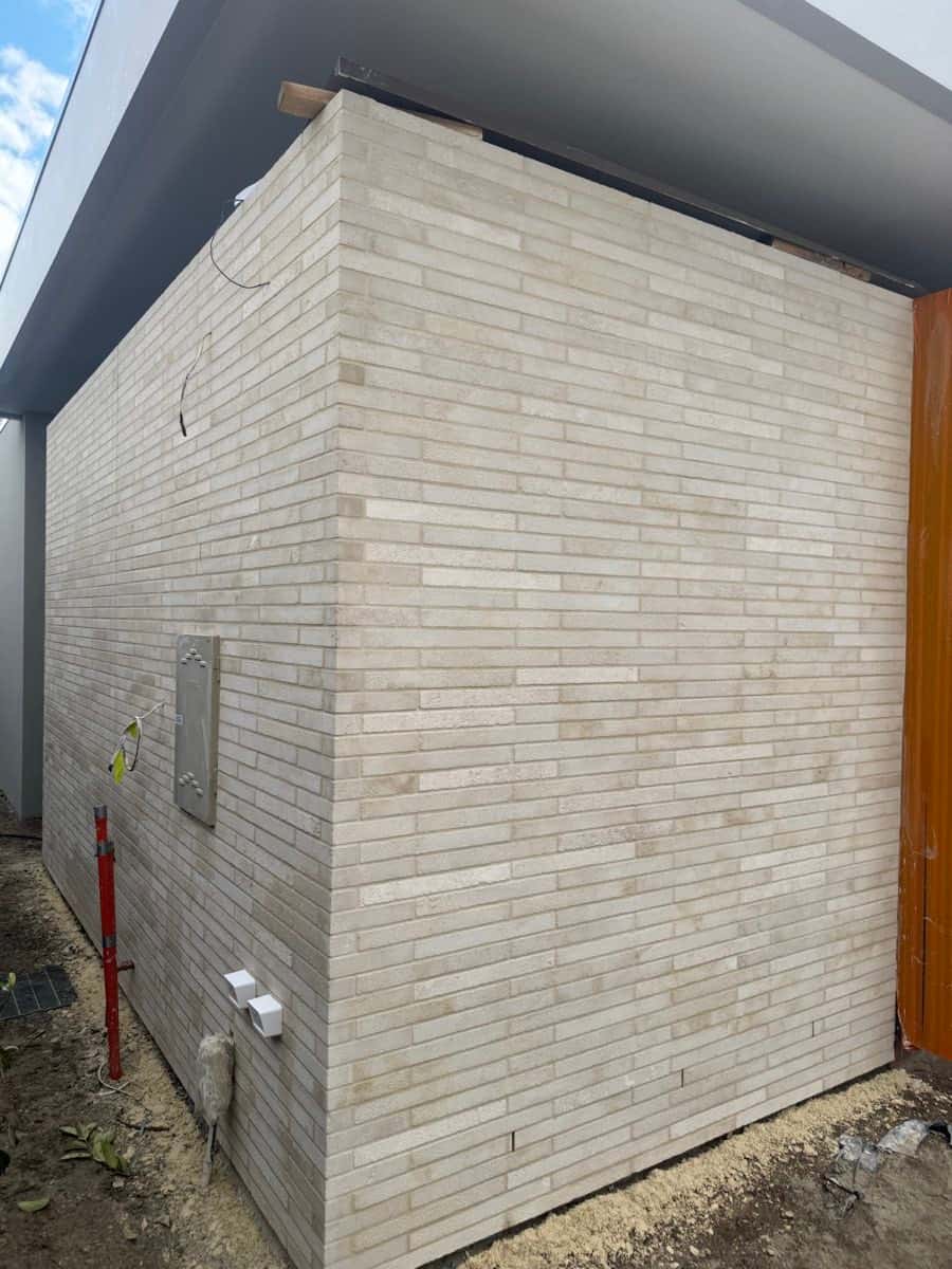 Exterior wall finished in slim horizontal light-toned brick-style tiles.